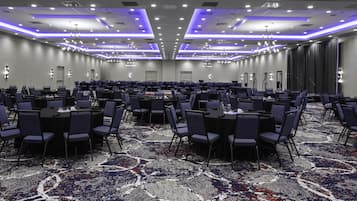 A large conference room with rows of tables and chairs, a patterned carpet, and modern lighting fixtures.