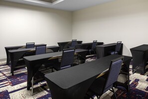 A conference room with multiple tables and chairs, carpeted floor, and plain walls. - Hilton Garden Inn Denison/Sherman/At Texoma Event Center (Denison)