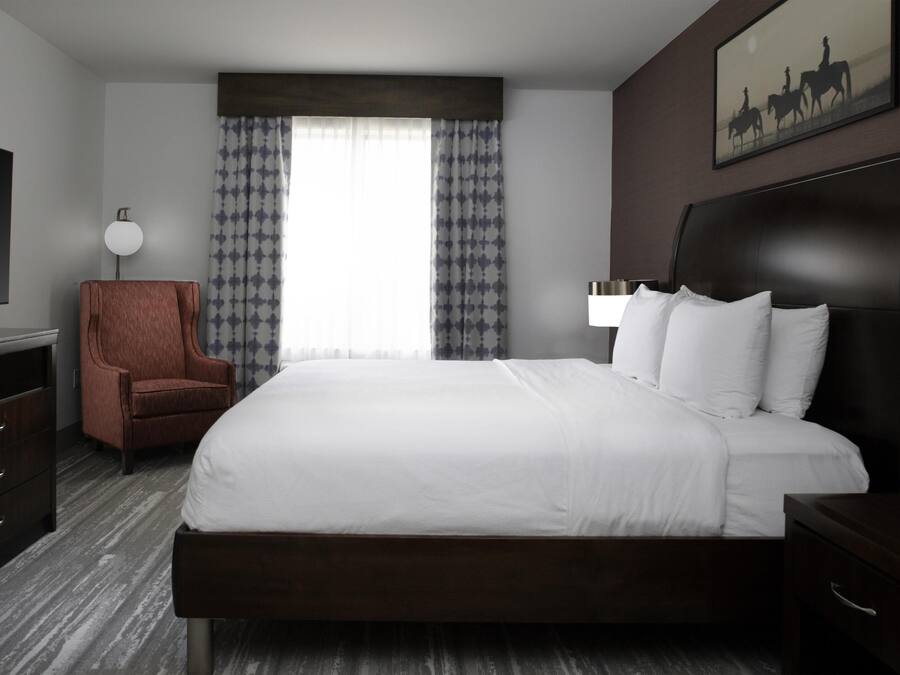 Una habitación de hotel con una cama grande, una silla, un escritorio y un televisor.