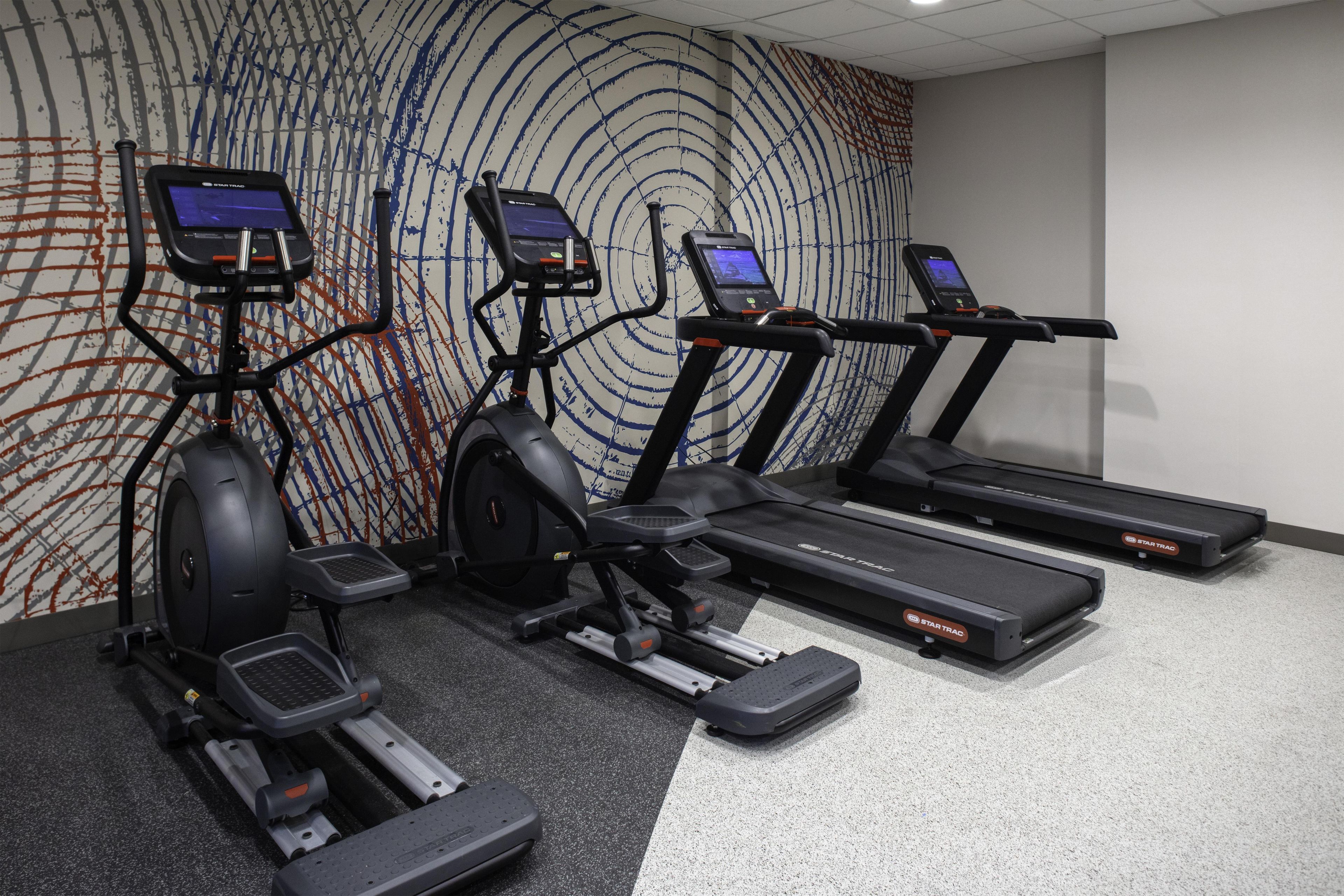 A gym with treadmills, elliptical machines, and stationary bikes.