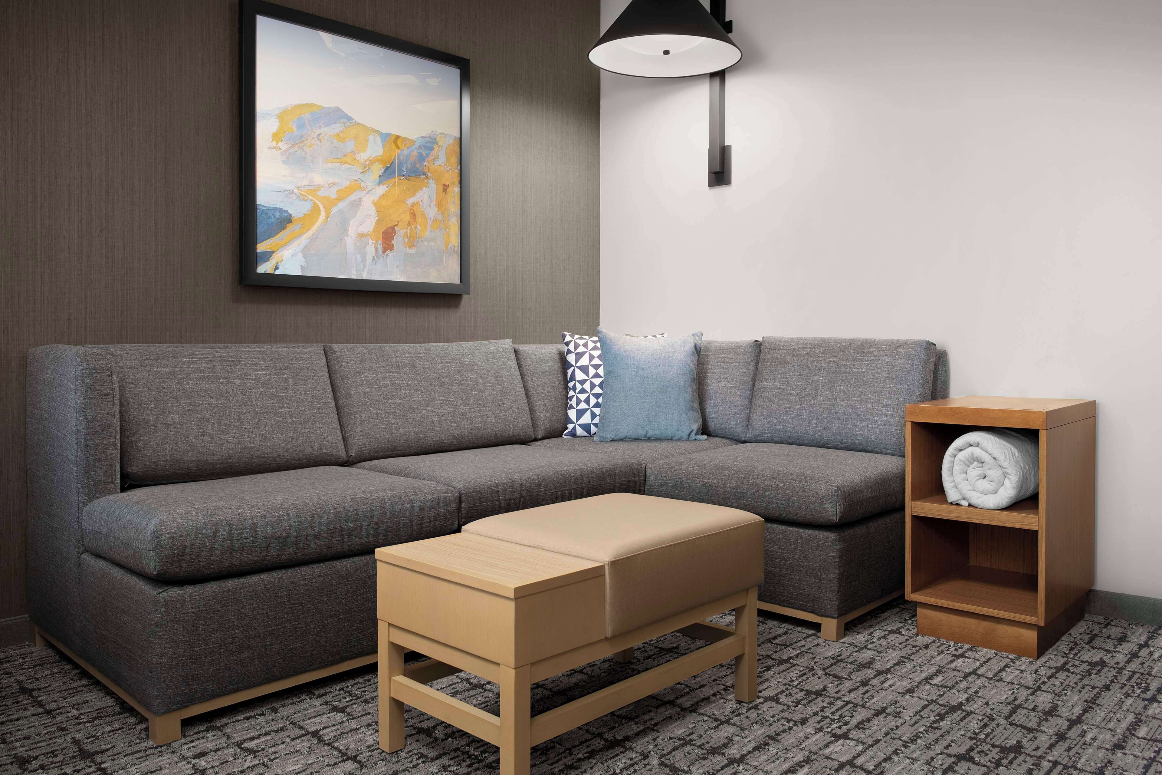 A modern living room with a grey sofa, a wooden side table, and a sideboard with a rolled-up blanket.