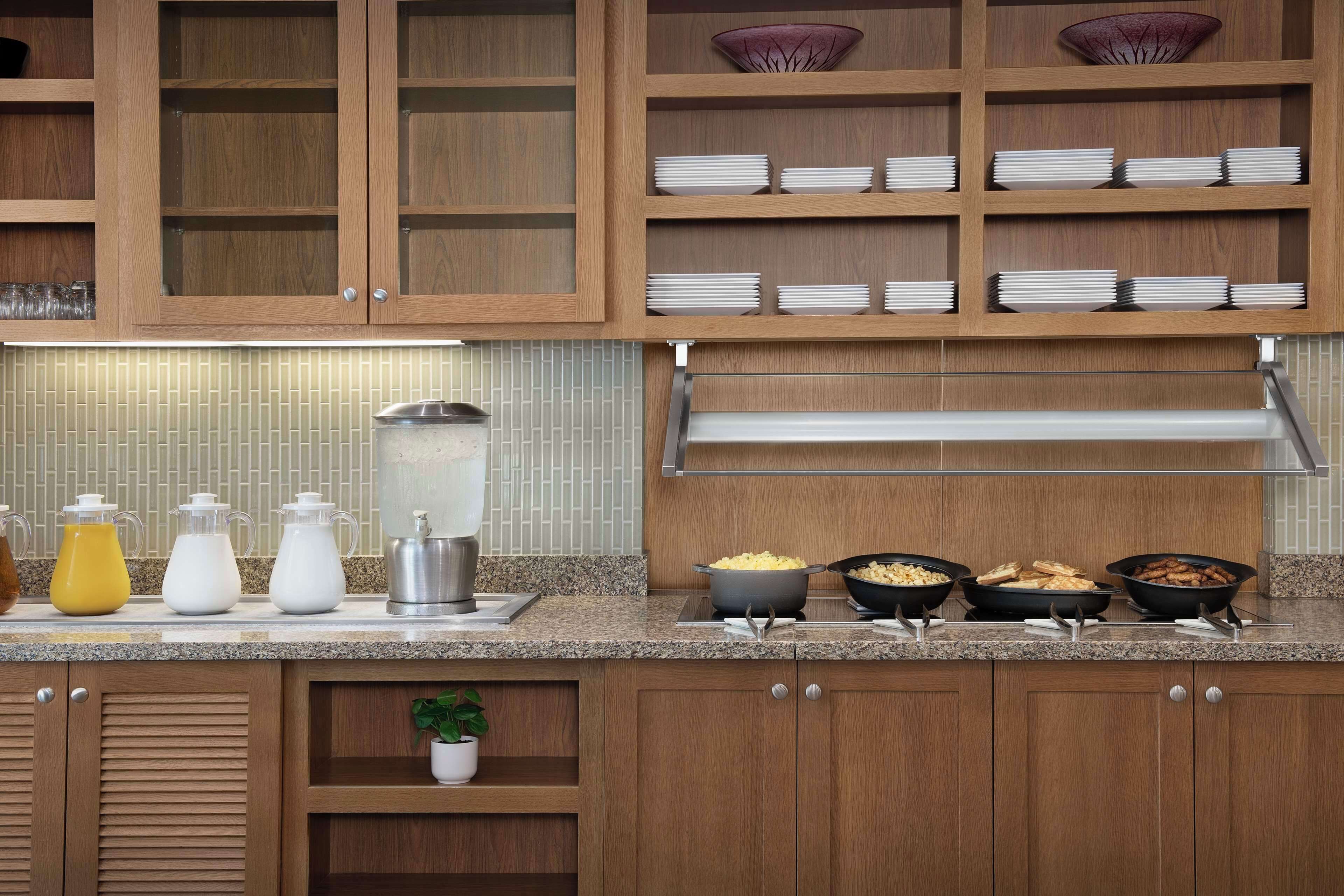 A kitchen with wooden cabinets, a tiled backsplash, and various kitchen appliances and utensils on the counter.