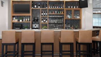 A bar area with multiple shelves of bottles, a coffee machine, and a flat-screen TV.