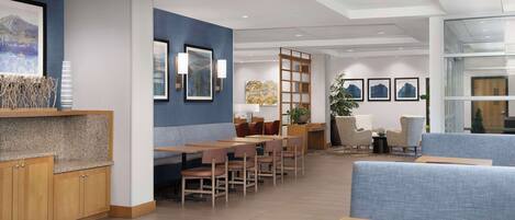 A modern hotel lobby with a seating area, wooden cabinets, and artwork on the walls.