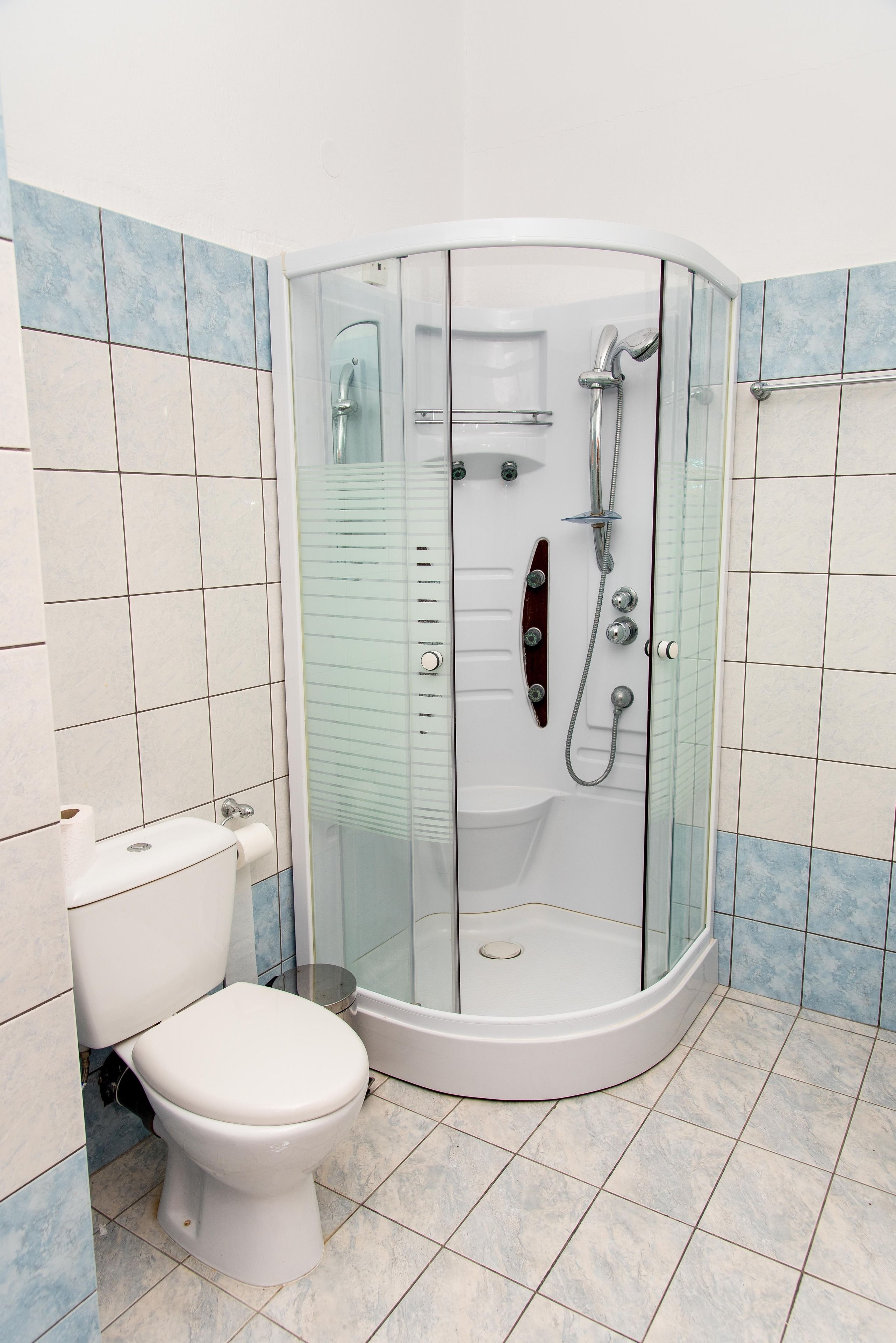 A modern bathroom with a glass-enclosed shower, a toilet, and tiled walls.