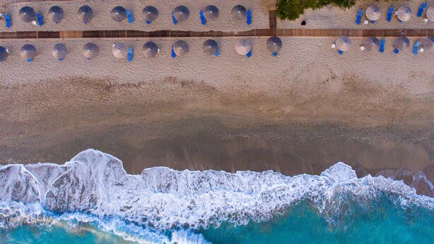An aerial view of a beach with a sandy shore and waves crashing onto it. - Poseidon Beach Hotel (Preveza)