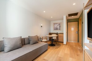 Una sala moderna con sofá, una mesa de comedor y una cocina al fondo.