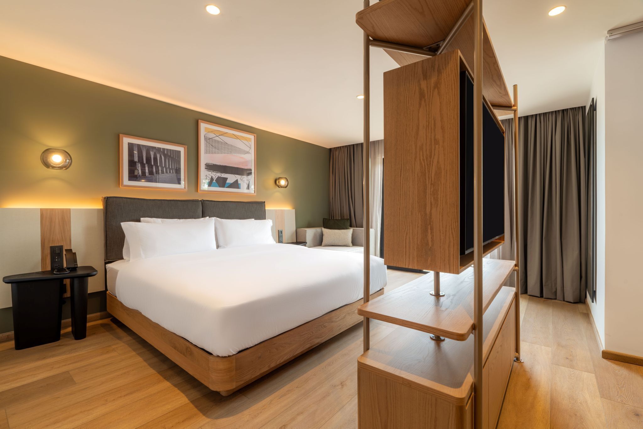 Habitación de hotel con una cama grande, televisión y obras de arte en la pared.