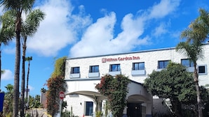 A Hilton Garden Inn with a white exterior, multiple windows, and a sign indicating the entrance.