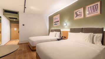 Une chambre d’hôtel avec deux lits, un bureau et une lampe fixée au mur.