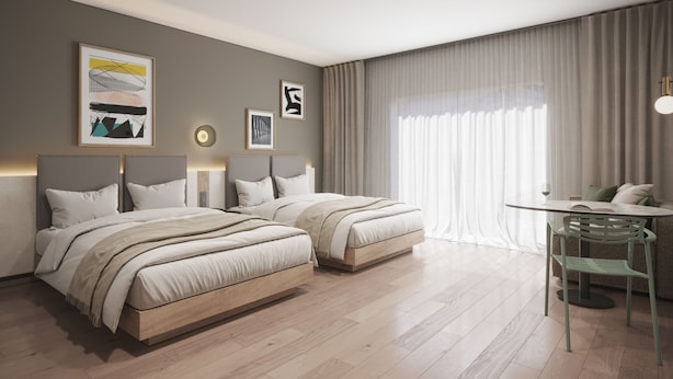 A hotel room with two beds, a small table, and a chair.