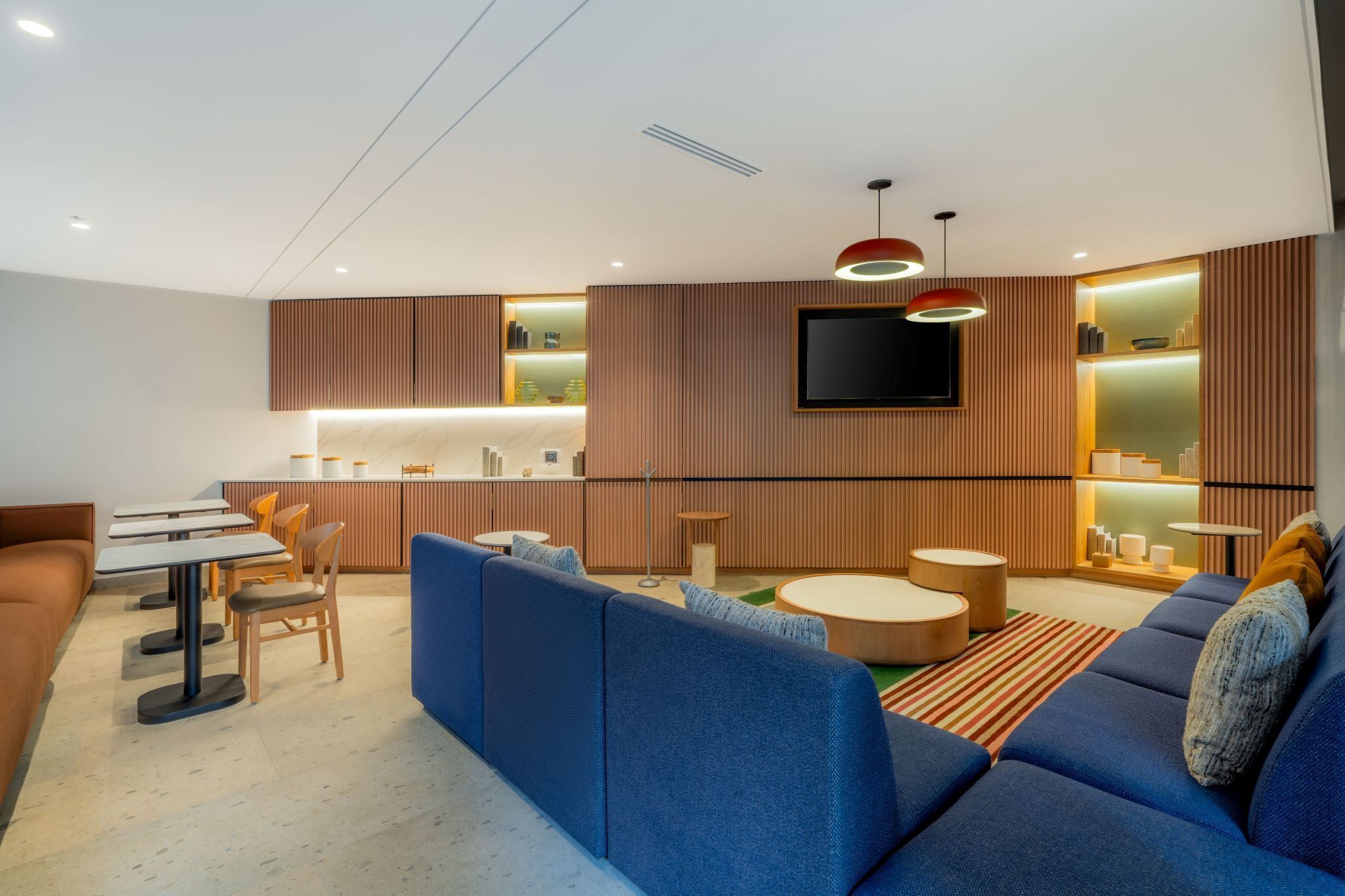 Una sala de estar moderna con un sofá, una mesa de centro y un televisor montado en la pared.