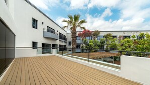 A modern building with a wooden deck, glass railings, and a palm tree. - Hilton Garden Inn Tijuana Airport (Tijuana)
