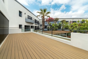 A modern building with a wooden deck, glass railings, and a palm tree. - Hilton Garden Inn Tijuana Airport (Tijuana)