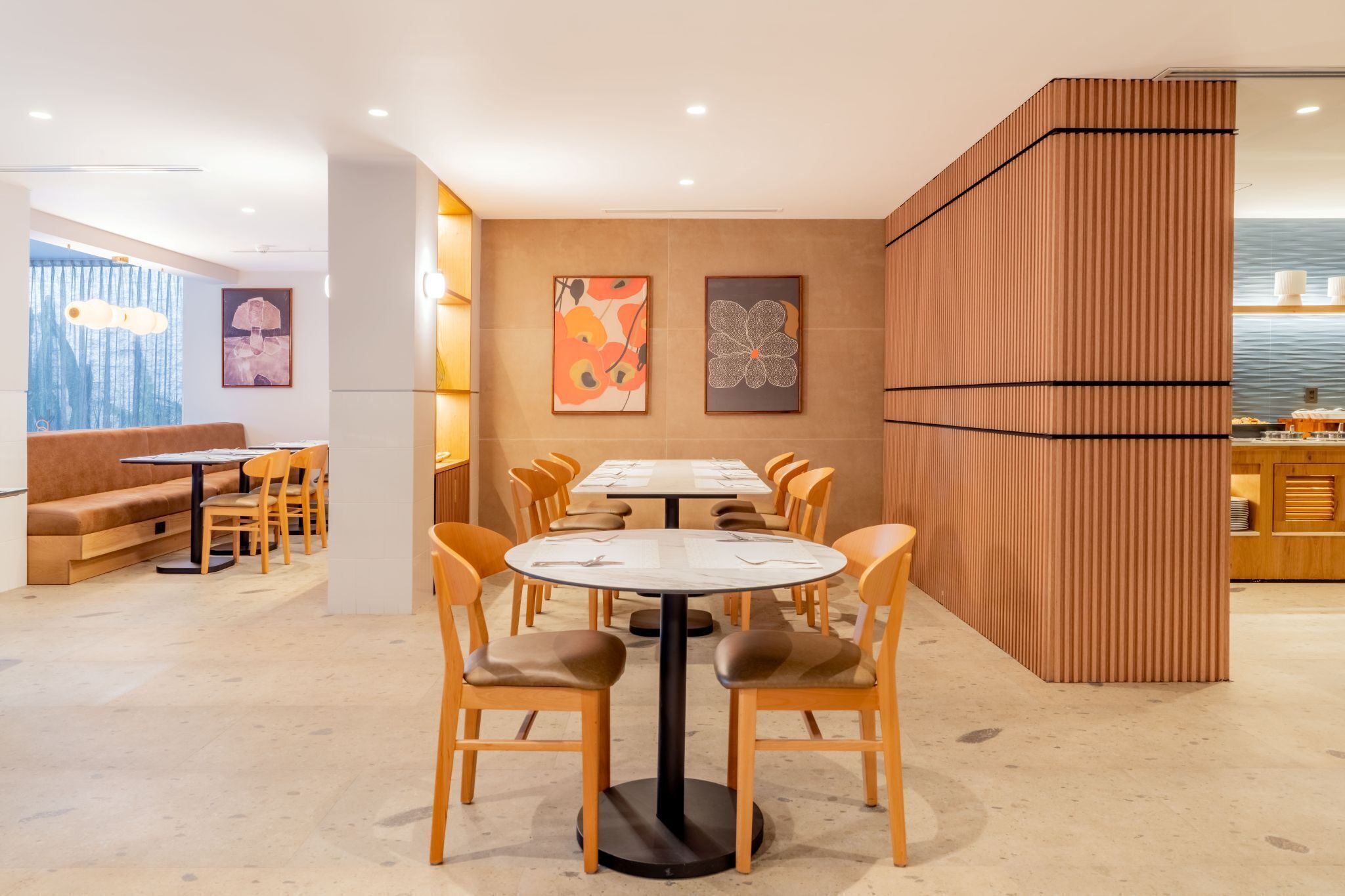 Un comedor moderno con mesas y sillas redondas, un sofá y obras de arte en las paredes.