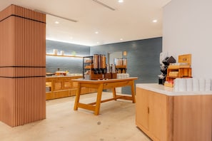 A modern cafe interior with a wooden counter, a seating area, and a wall-mounted coffee machine. - Hilton Garden Inn Tijuana Airport (Tijuana)