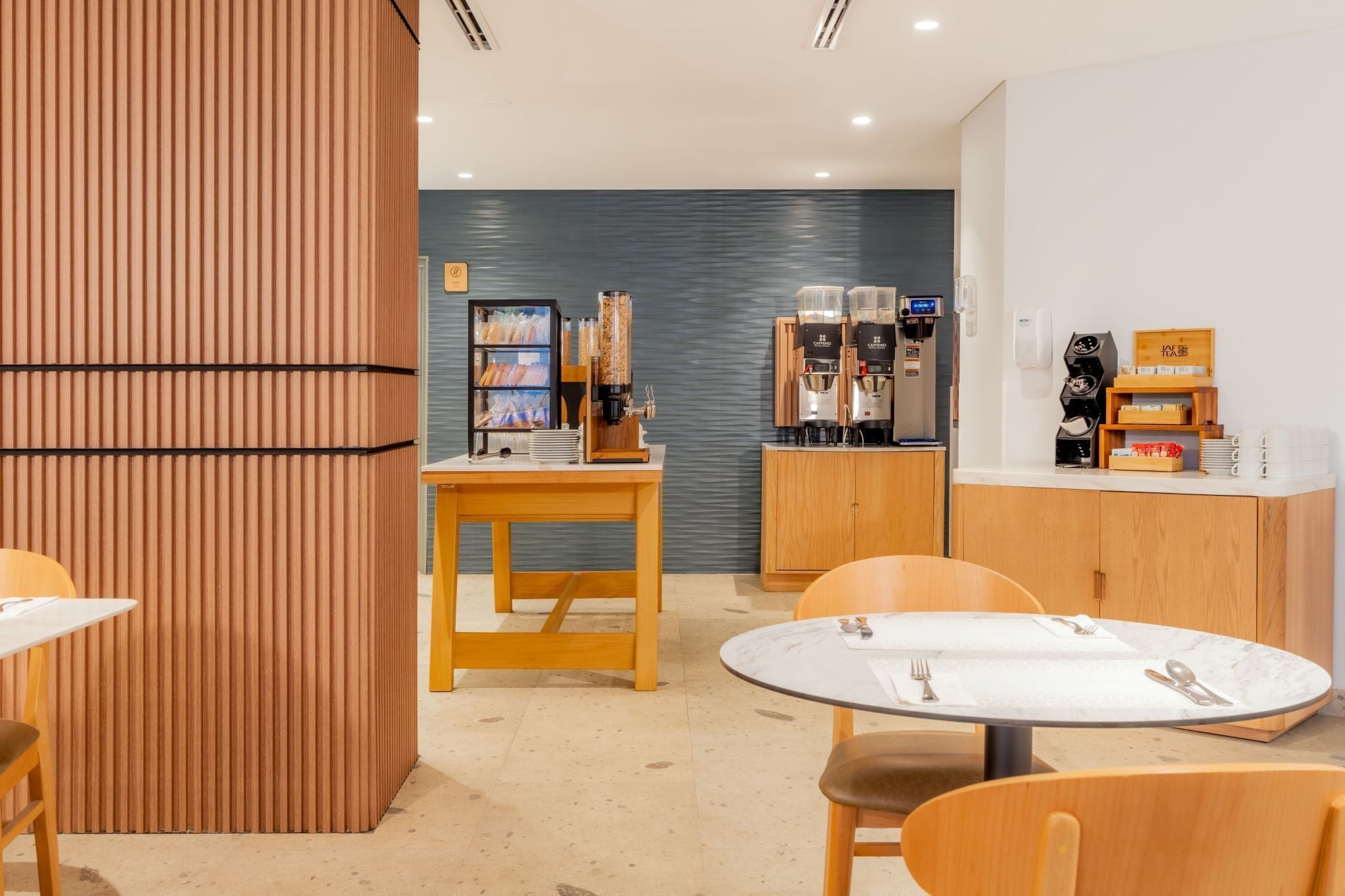 A modern cafe with wooden furniture, a coffee machine, and a counter with a menu.