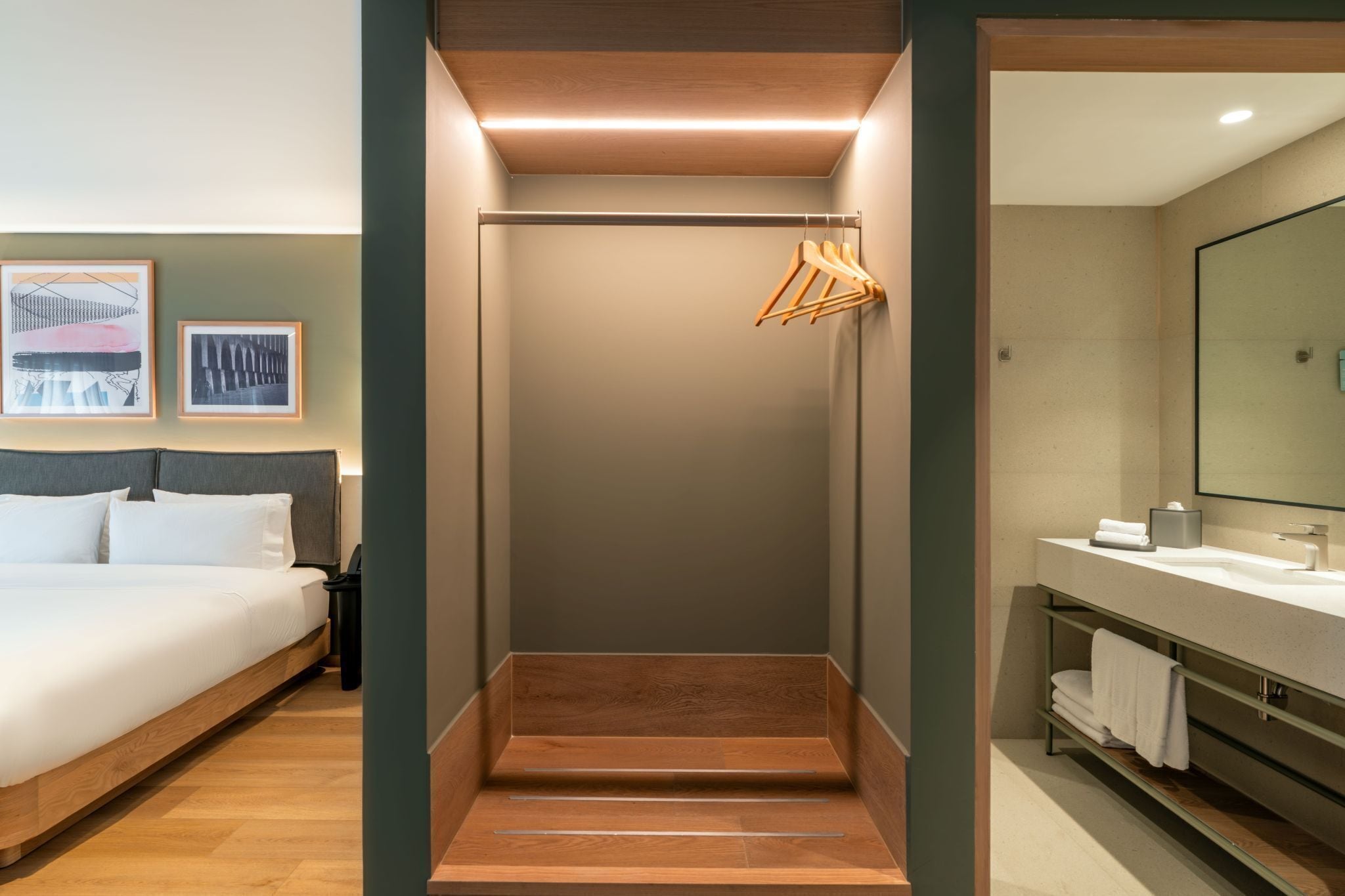 Una habitación de hotel con cama, zona de ducha y baño con espejo y toallero.