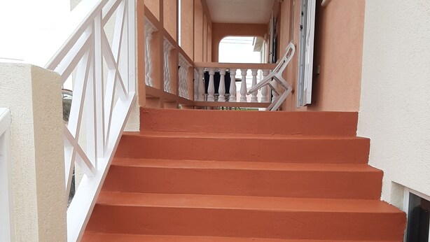 Eine Treppe mit weißen Geländern, die zu einer Zwischenebene führt.