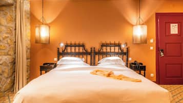 A double bed with white linens, a wooden headboard, and a red door.