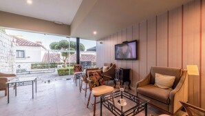 A modern living room with a TV, comfortable seating, and a view of the outside. - Pousada Castelo de Óbidos - Historic Hotel (Obidos)