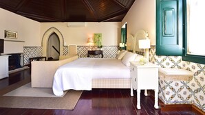 A bedroom with a bed, a nightstand, a dresser, a mirror, and a window with a green door. - Pousada Castelo de Óbidos - Historic Hotel (Obidos)