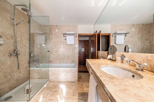 A modern bathroom with a glass-enclosed shower, a separate bathtub, and a large vanity with a sink and mirror.