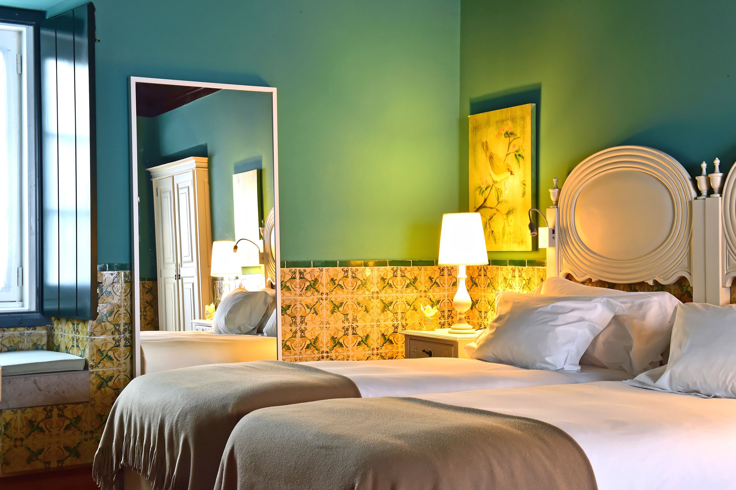 Ein Hotelzimmer mit Bett, Nachttischen, einem Spiegel und einer Wand mit Blumenmuster.
