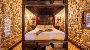 A four-poster bed with a stone wall backdrop, a wooden ceiling, and a patterned floor. - Pousada Castelo de Óbidos - Historic Hotel (Obidos)