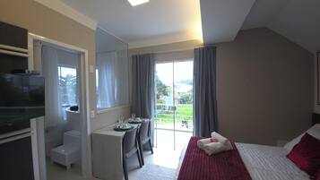 A hotel room with a bed, a desk, a television, and a view of the outdoors.