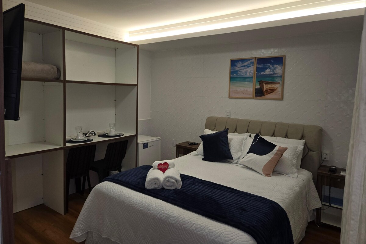 A hotel room with a bed, a desk, and a wardrobe.