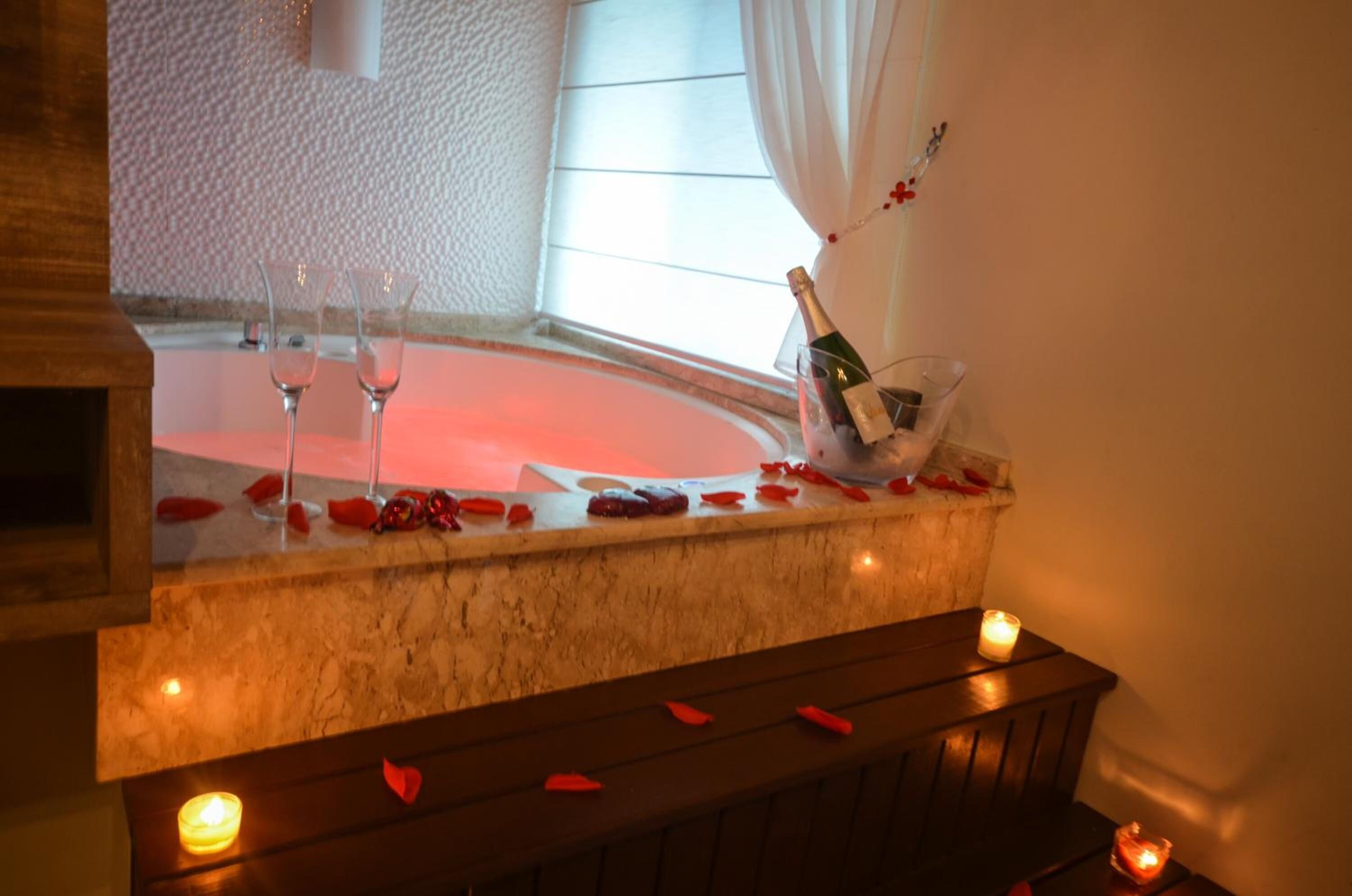 Un comptoir en marbre avec deux verres, une bouteille de champagne et des pétales de rose.
