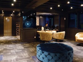 A modern lounge area with a bar, seating, and a patterned carpet.