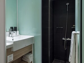 A modern bathroom with a white sink, mirror, and black tiled shower. - Hotel Relax II (Taipei)