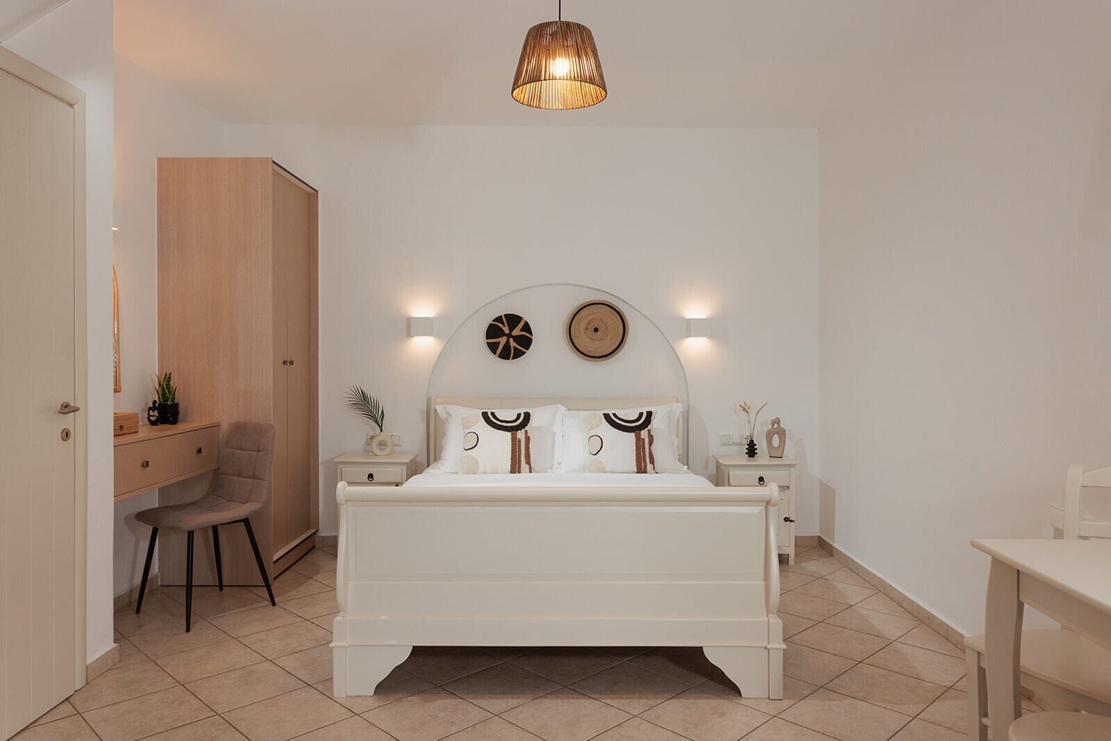 Un dormitorio con cama, mesitas de noche, una silla, escritorio y armario.