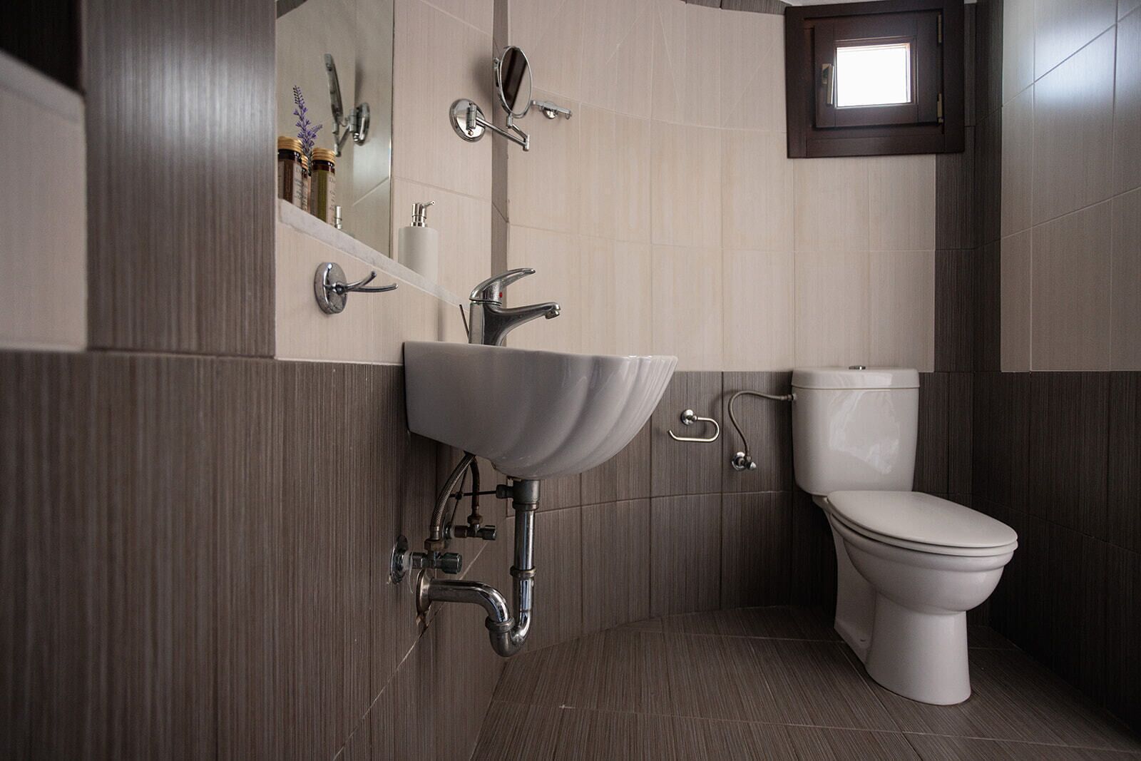 A modern bathroom with a white sink, a toilet, and a mirror.