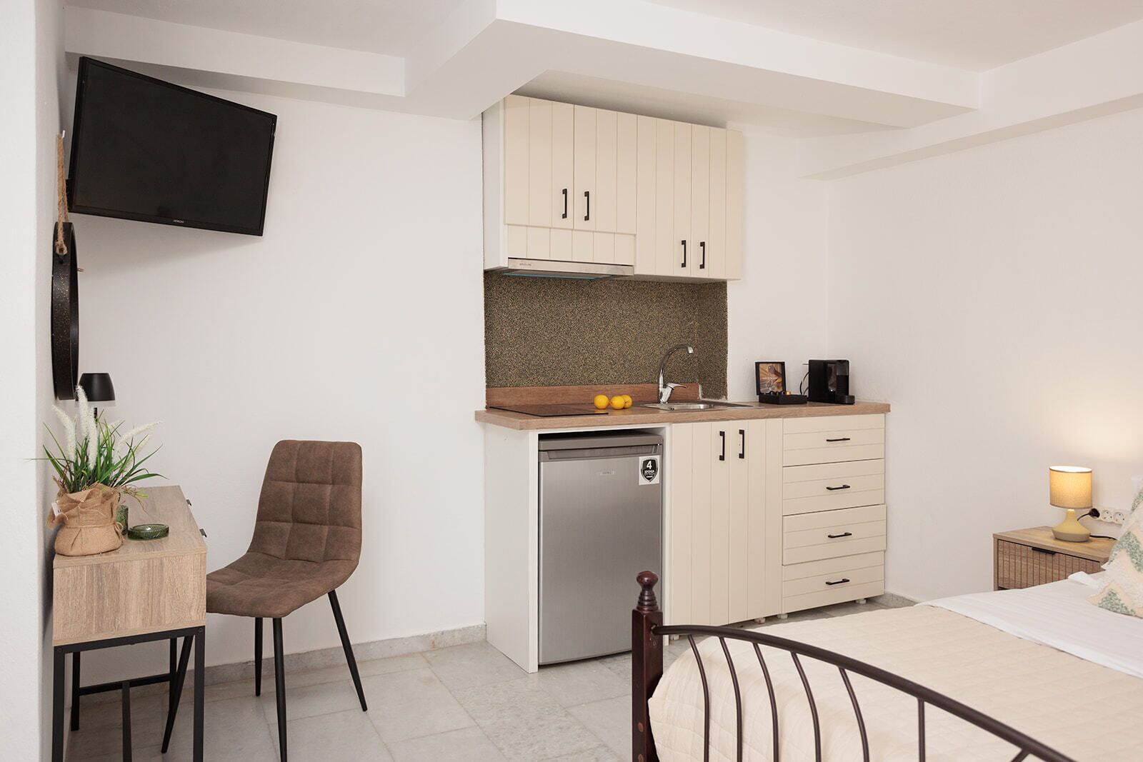 Una kitchenette compacta con lavavajillas integrado, una pequeña mesa de comedor y una silla.