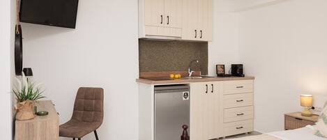 Una kitchenette compacta con lavavajillas integrado, una pequeña mesa de comedor y una silla.
