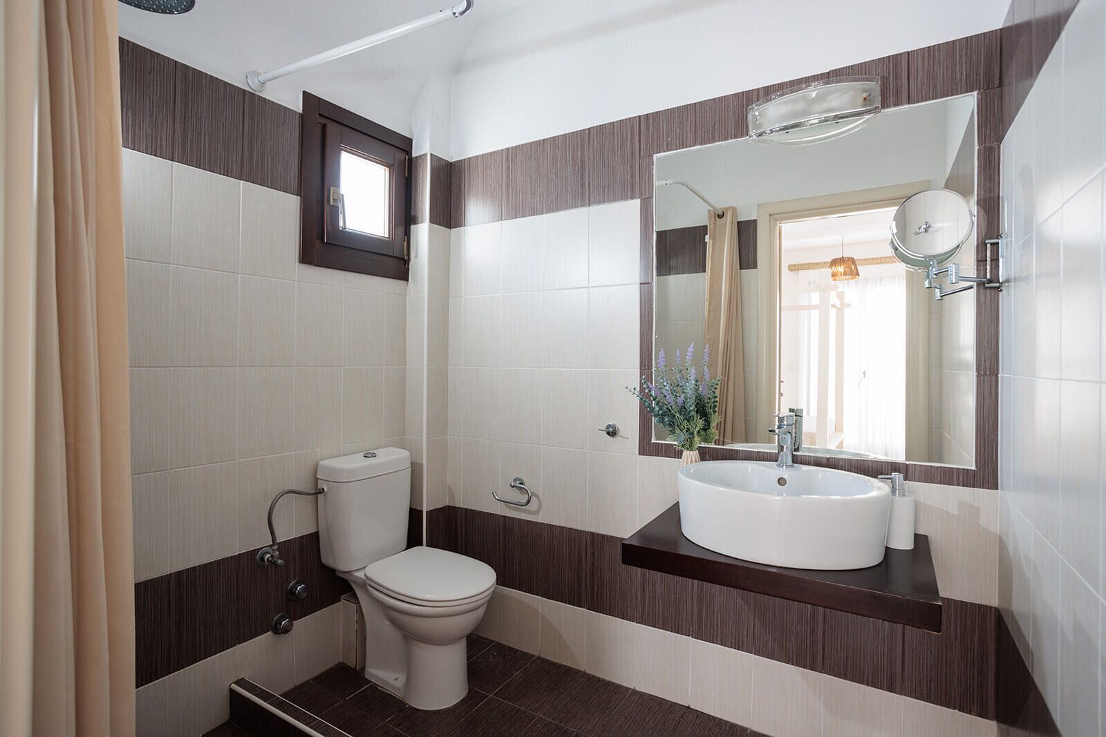 Un baño moderno con inodoro, lavamanos y espejo.
