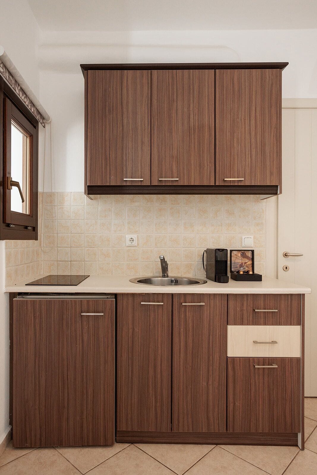 A kitchen with wooden cabinets, a sink, and a coffee maker.