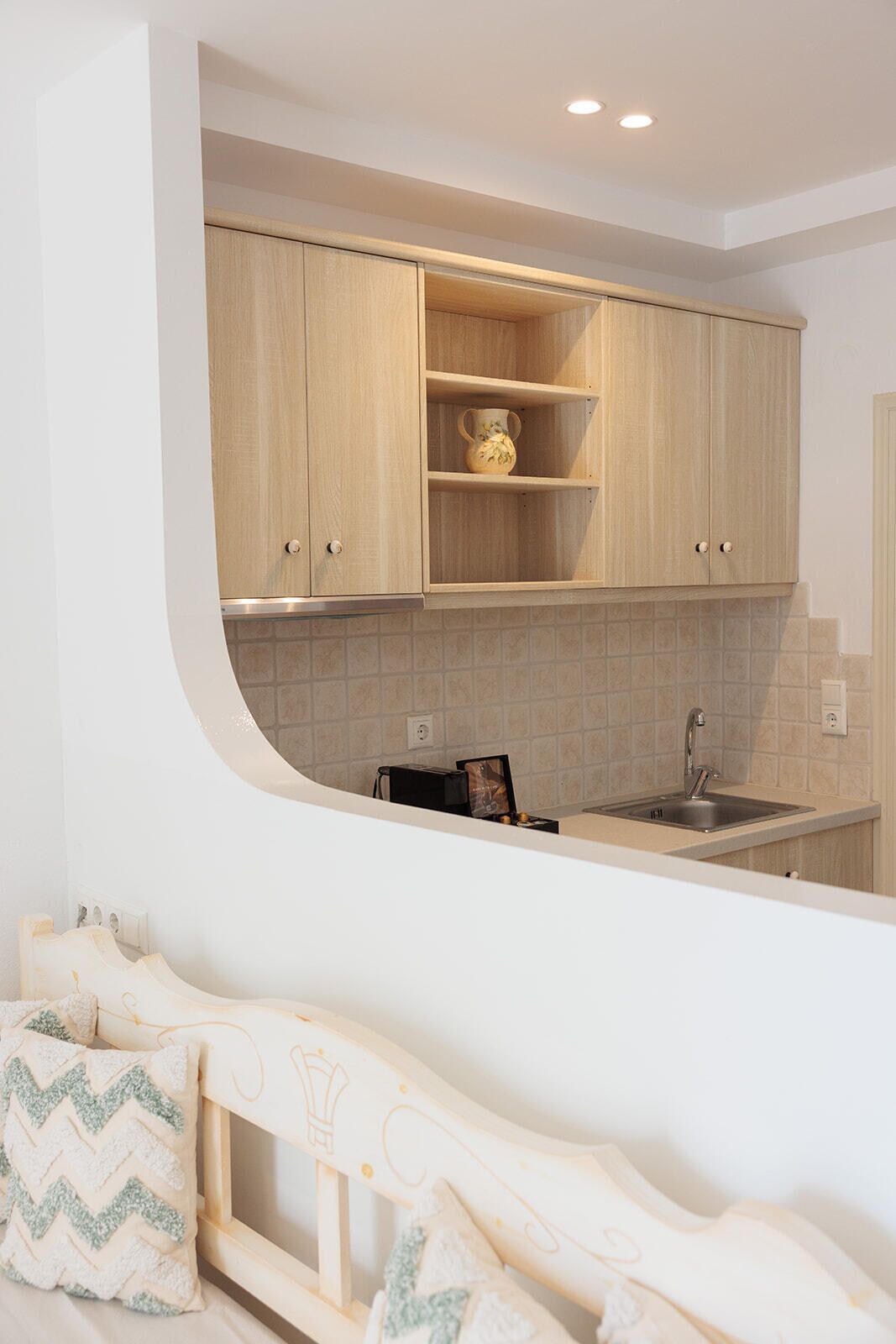 A modern kitchen with light wood cabinets, a built-in sink, and a curved countertop.
