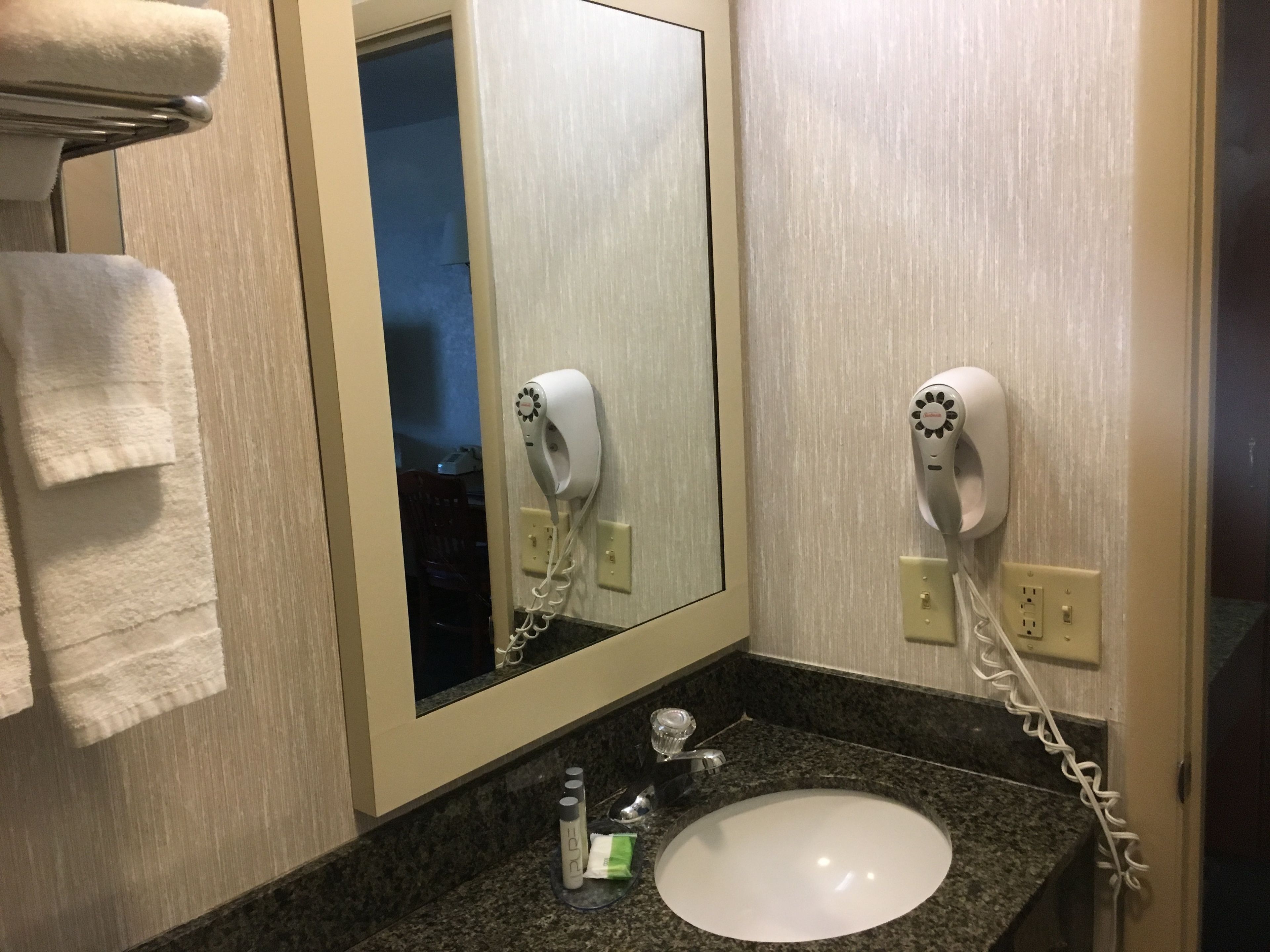 Un bagno con lavandino, portasciuga asciugamani e due asciugacapelli fissati alla parete.