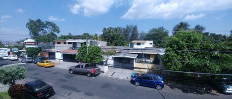 Vista de la calle con coches aparcados, edificios y cielo despejado.