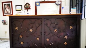 Una mesa de recepción con acabado de madera oscura y detalles metálicos decorativos.