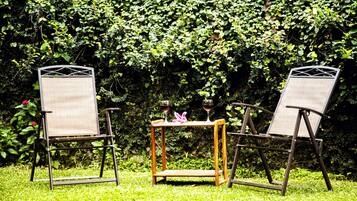 Duas cadeiras e uma pequena mesa com dois copos de vinho em um jardim.