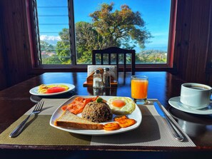 Una mesa de desayuno con platos de comida, un vaso de jugo de naranja y una taza de café.