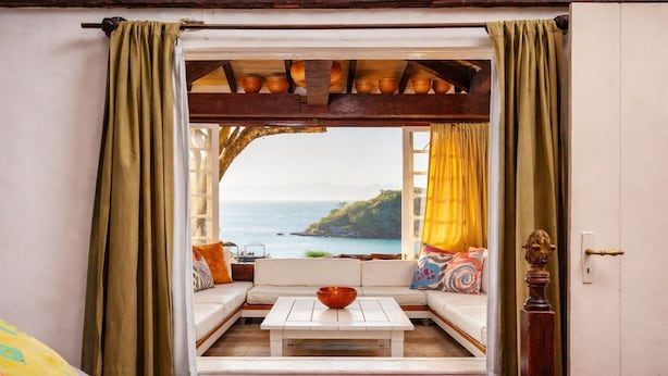 Ein Zimmer mit Meerblick, ein weißes Sofa, ein Holztisch und ein roter Teppich.