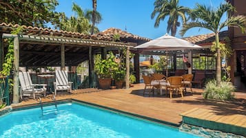 Una piscina al aire libre, sillones reclinables de piscina