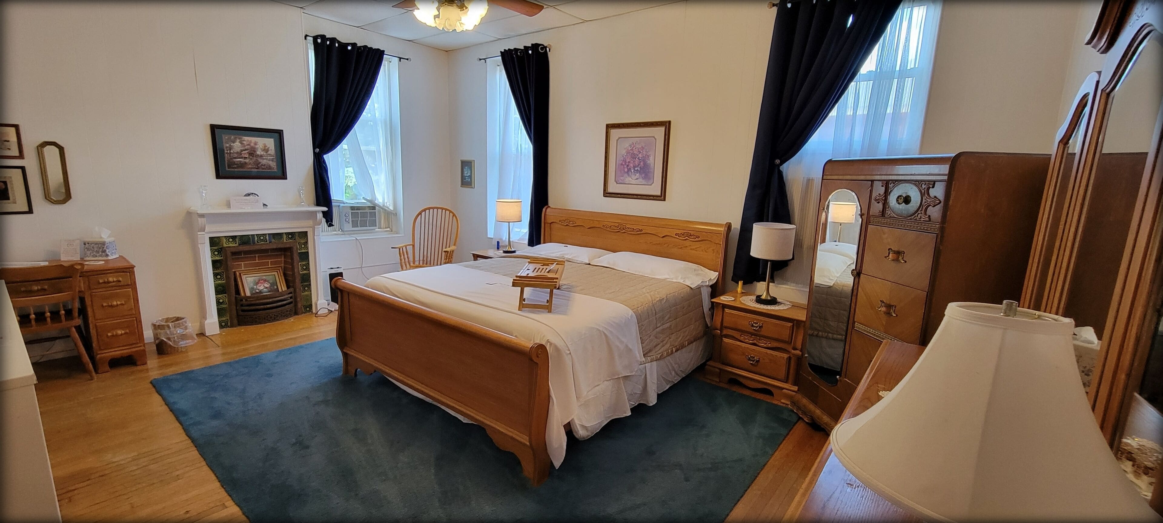 A neatly arranged bedroom with a wooden bed, a dresser, a chair, and a desk.