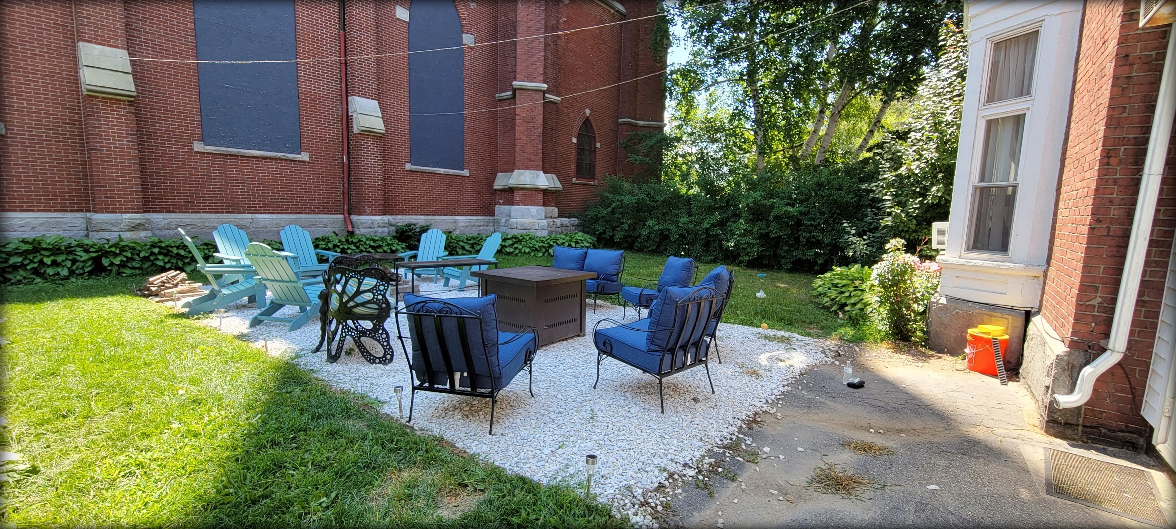 A patio area with outdoor seating, a brick building, and a grassy lawn.